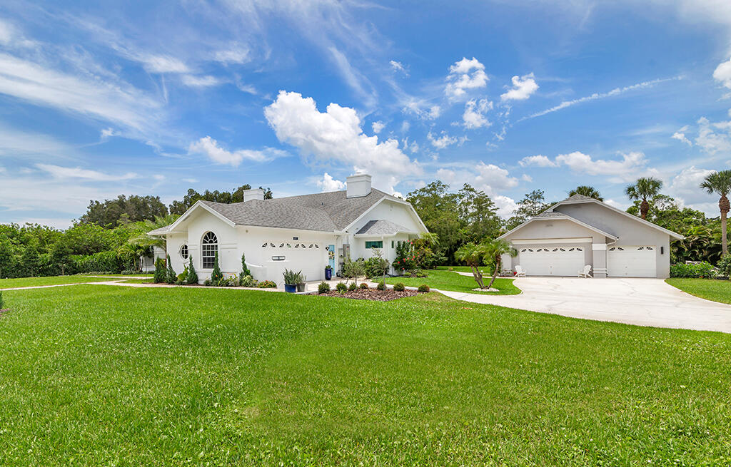 White single-story home with an arched window, broad lawn, and two-car garage to the right.
