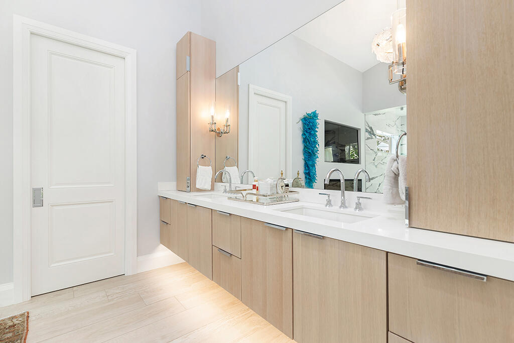 Modern bathroom with a long light-wood double vanity and wall-length mirror.