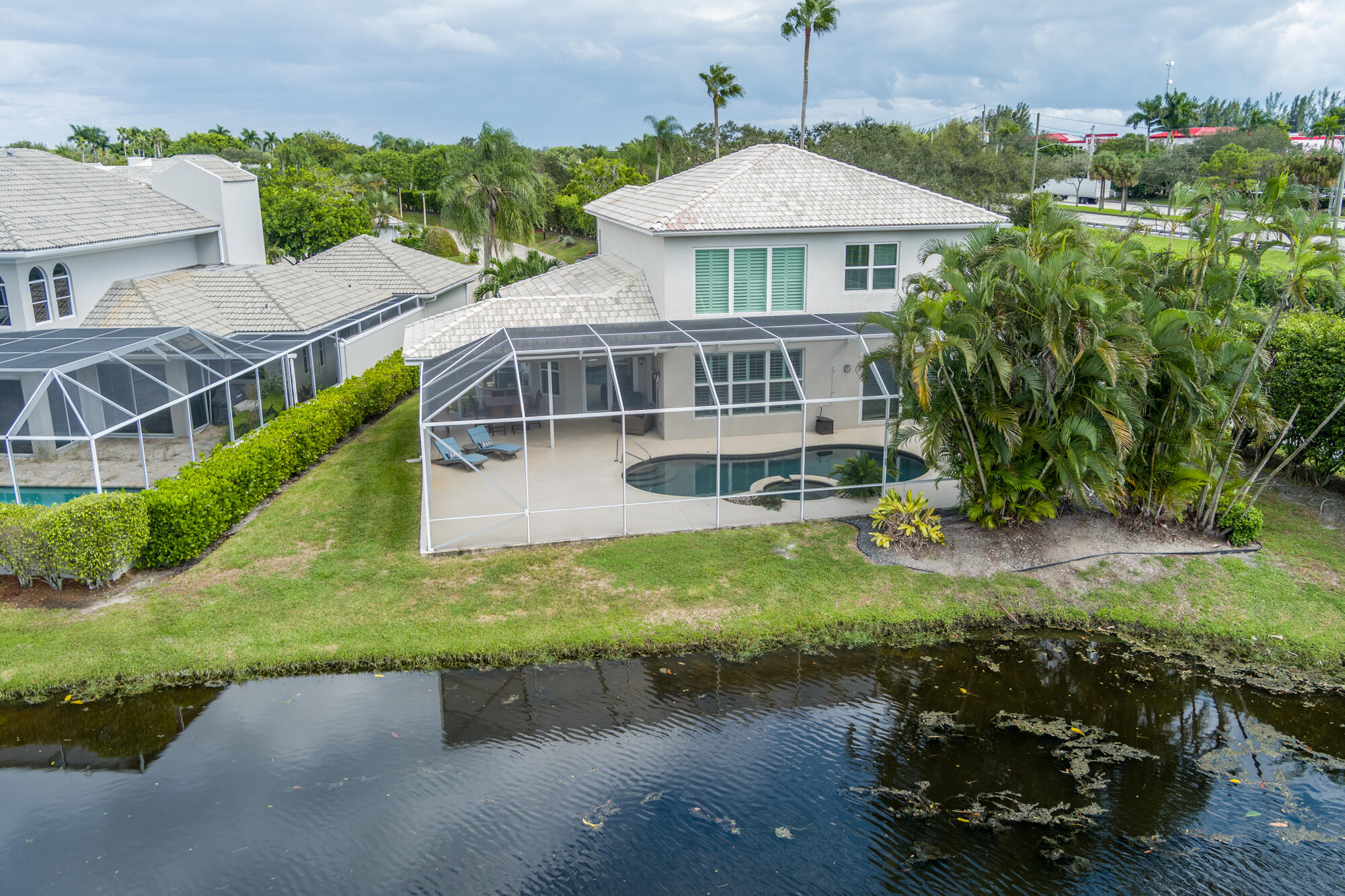 Rear of a two-story home with a screened pool beside a canal.