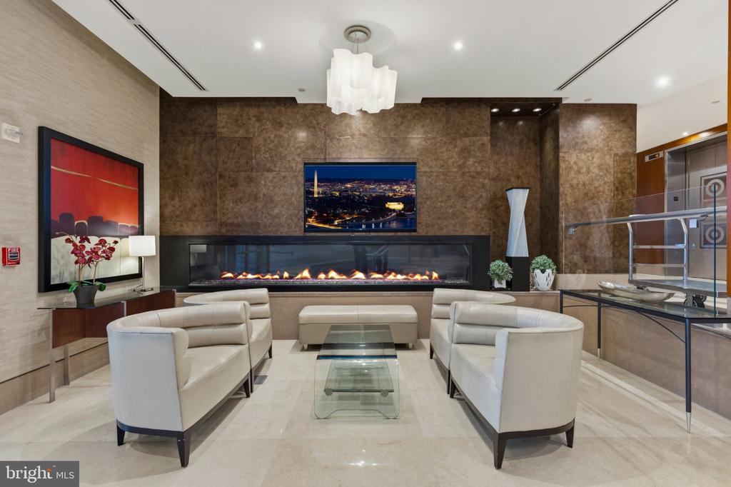 Condominium lobby with white sofas, a glass coffee table, and a long linear fireplace.