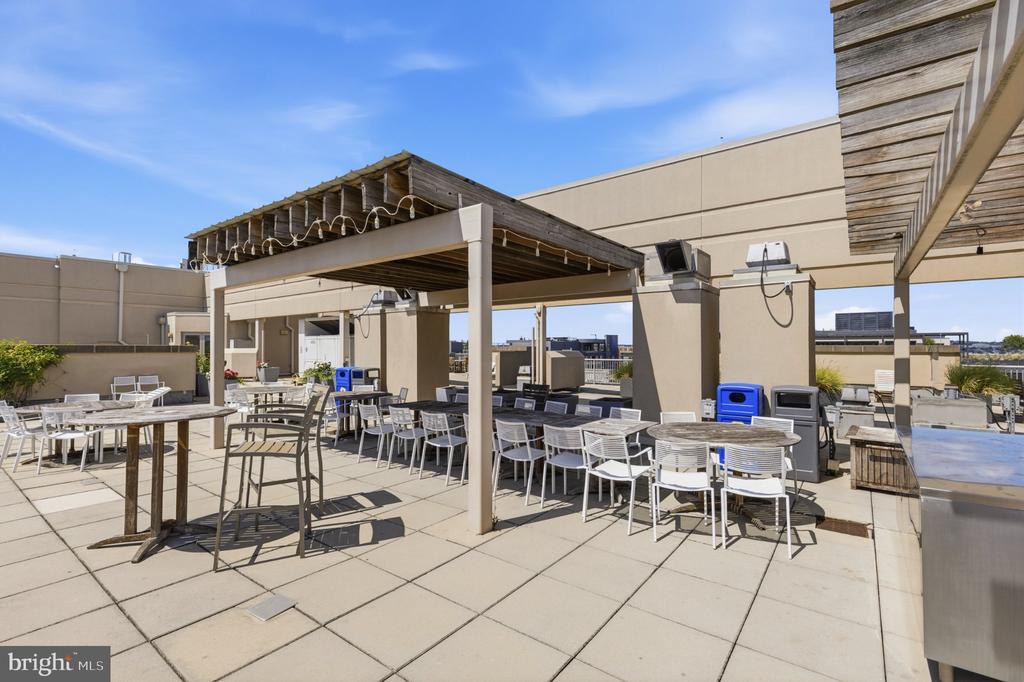 Rooftop terrace with outdoor seating beneath a wooden pergola.