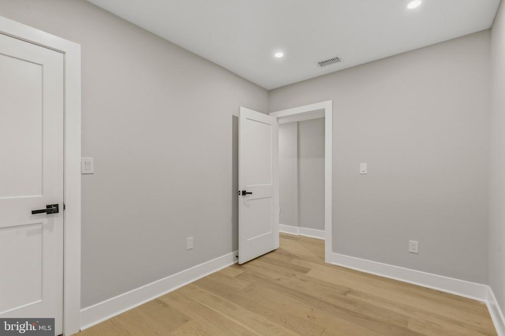 Empty room with light wood floors, gray walls, and an open doorway.