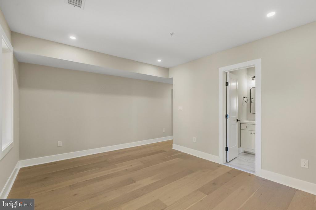 Vacant bedroom with light wood floors and an open doorway to a bathroom.