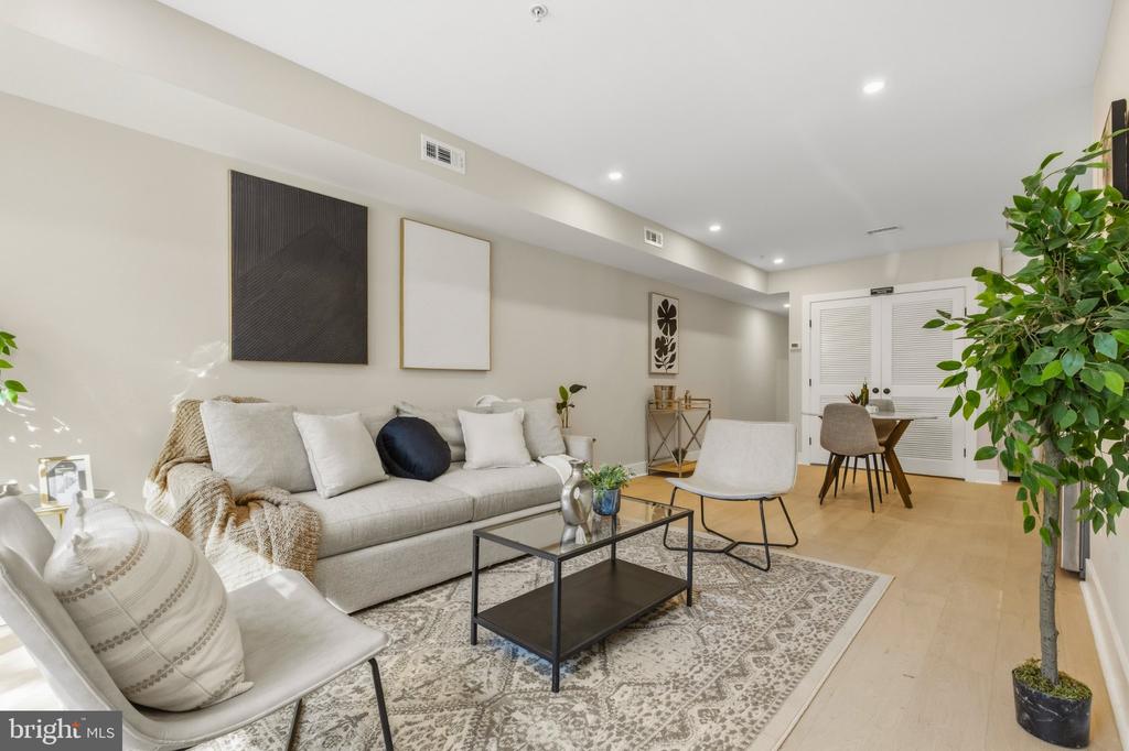 Living room with a light sofa, patterned rug, black coffee table, and dining nook.