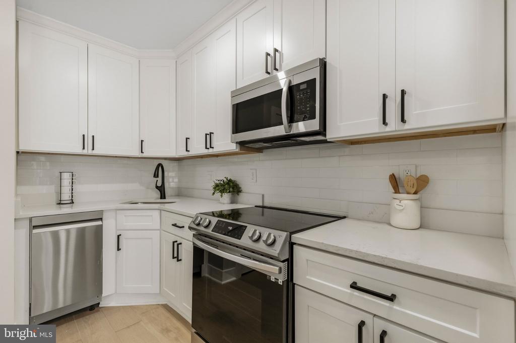 Kitchen with white cabinets, stainless steel appliances, and a white subway tile backsplash.