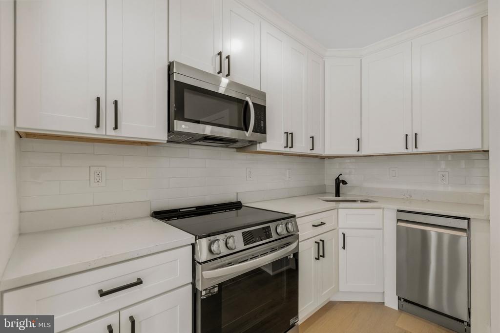 Kitchen with white cabinetry, stainless steel appliances, and a subway tile backsplash.