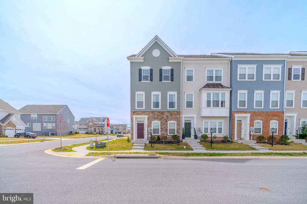 Gray corner townhouse with stone accents beside neighboring attached homes.