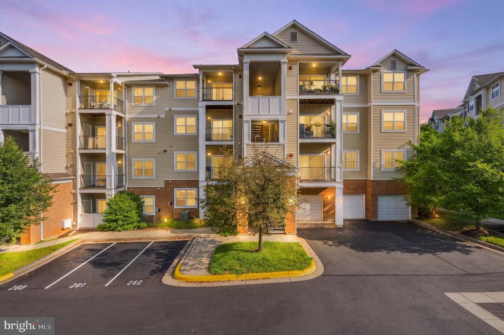 Multi-story condominium building with balconies and illuminated windows at dusk.