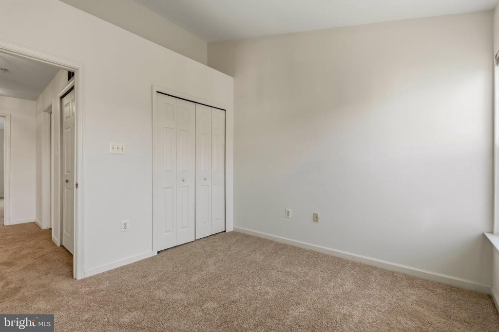 Empty bedroom with beige carpeting, white walls, and a double closet.