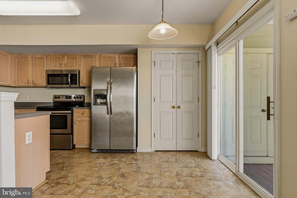 Kitchen with wood cabinets, stainless steel appliances, tiled floor, and sliding glass doors to a patio.