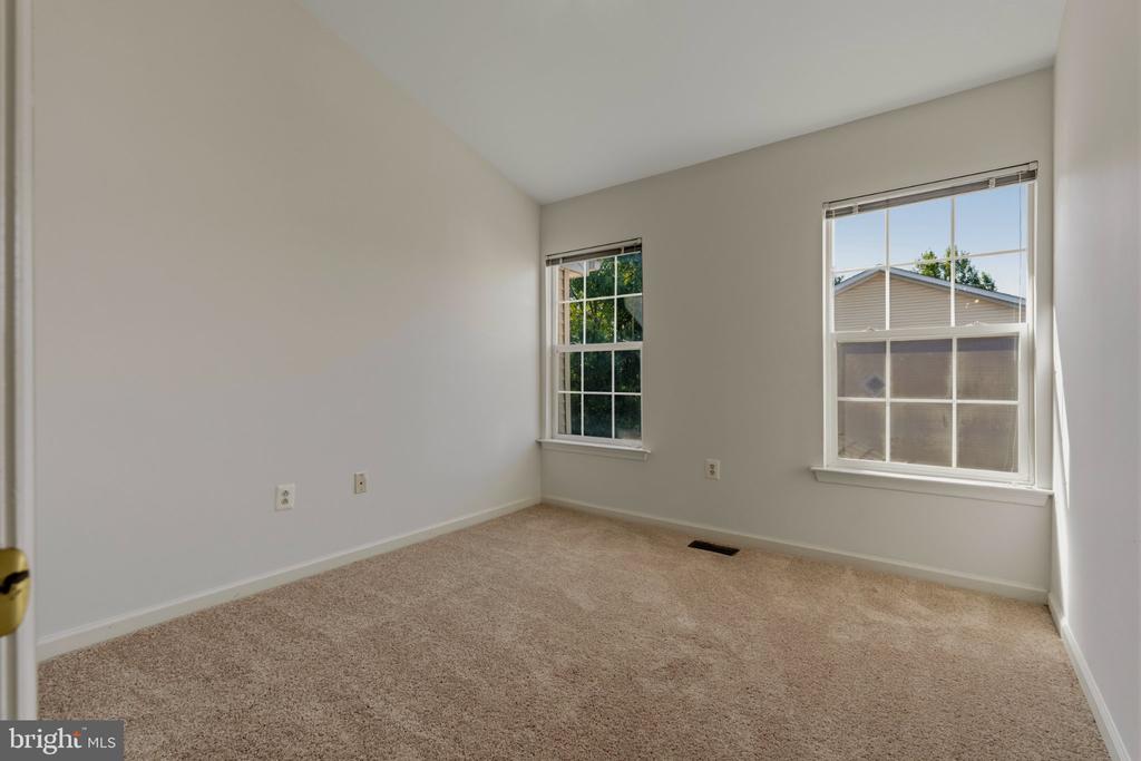 Empty carpeted bedroom with two windows and white blinds.