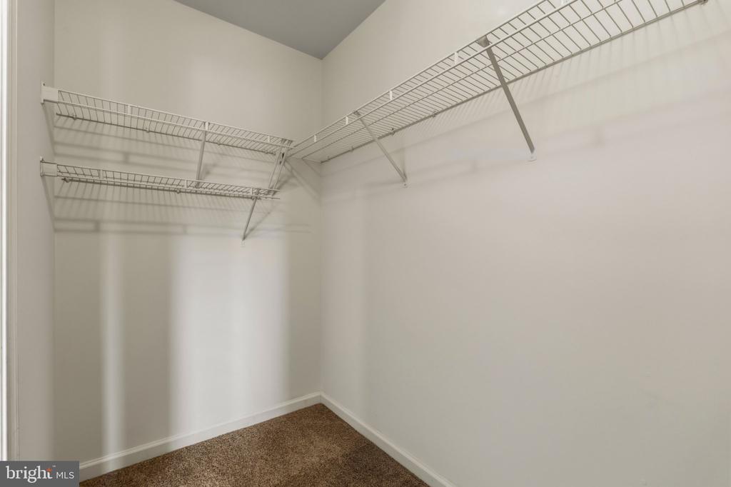 Walk-in closet with wire shelving along two walls and brown carpet.