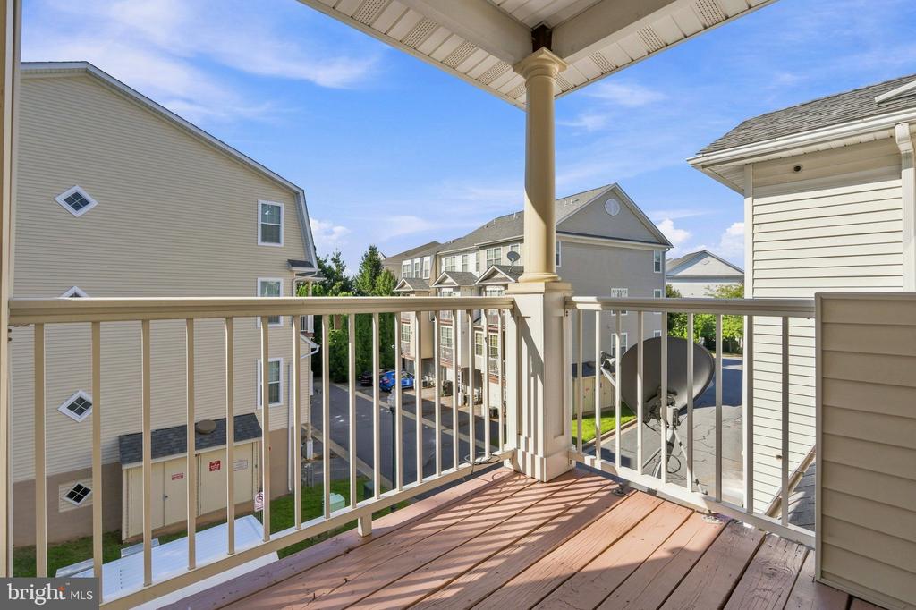 Covered balcony overlooking neighboring townhomes and a parking area.
