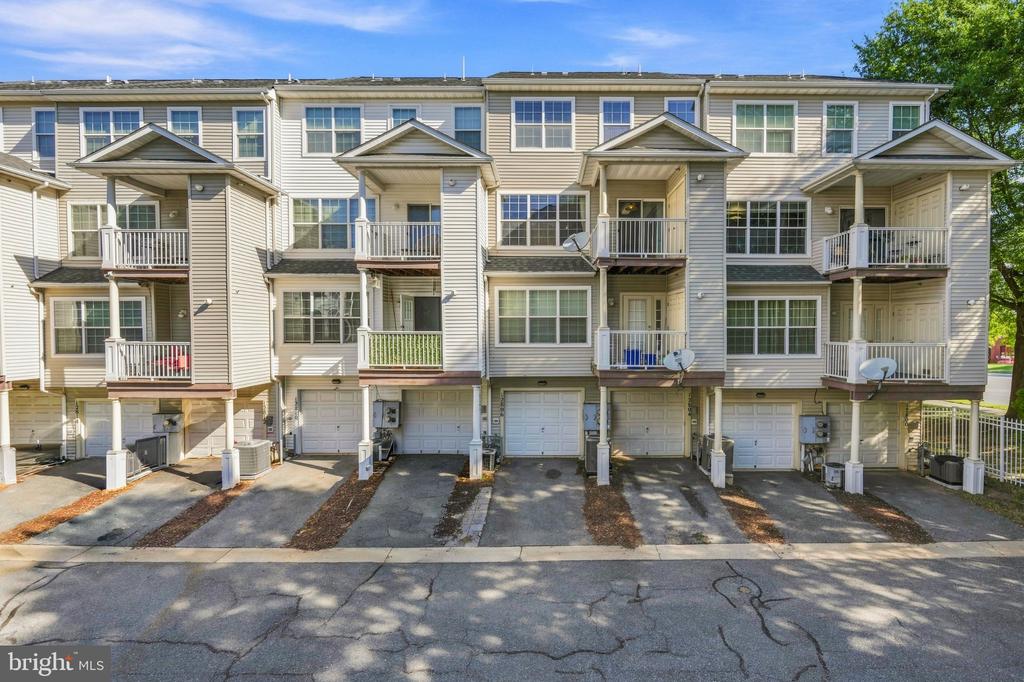 Attached homes with white garage doors, light siding, and rows of balconies.