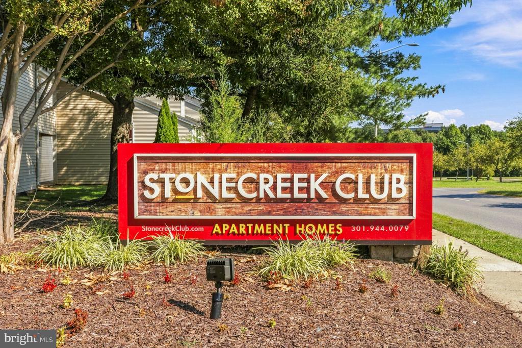 Stonecreek Club apartment community sign beside landscaped grounds.
