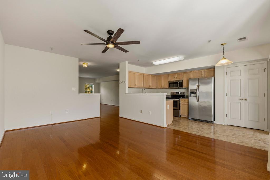 Open living area with hardwood floors and an adjoining kitchen with stainless steel appliances.