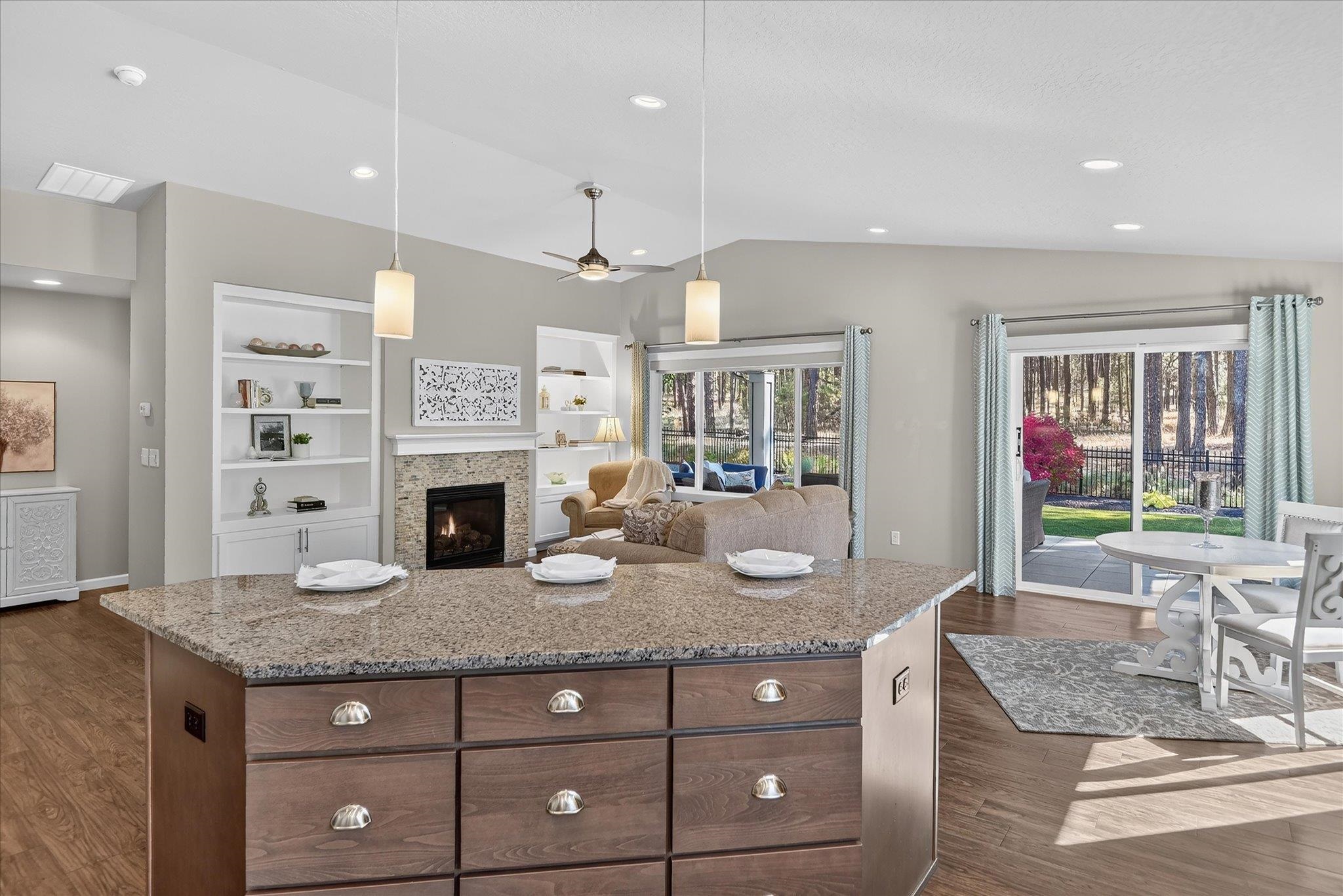 Open kitchen and living area with a granite island, fireplace, and sliding doors to the patio.