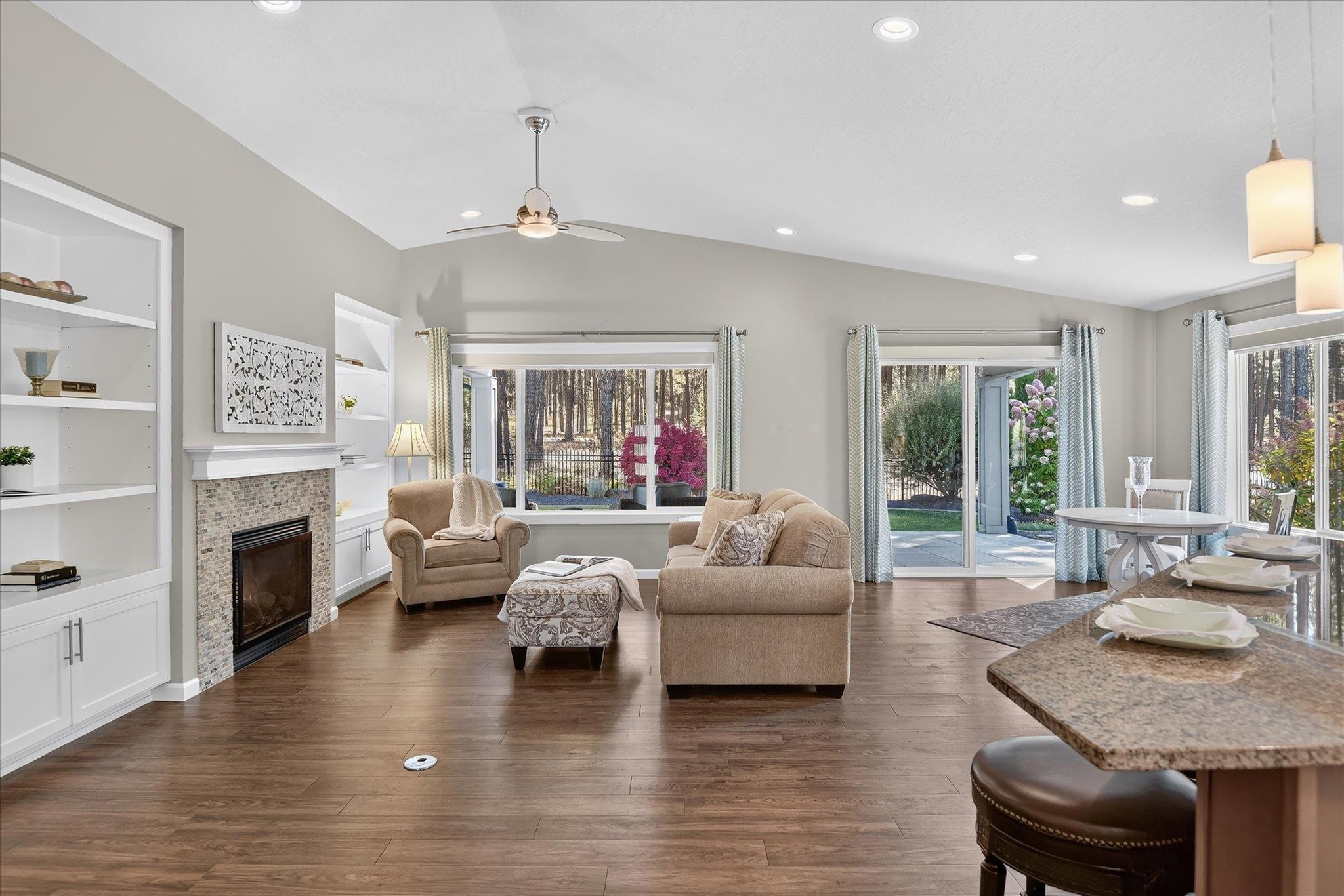 Living room with a stone-tile fireplace, vaulted ceiling, and sliding doors to a patio.