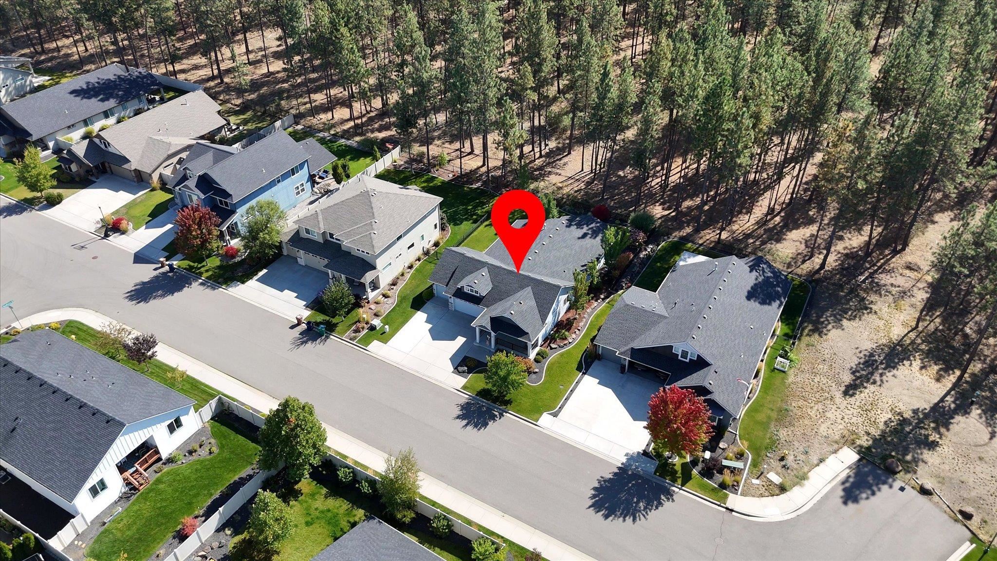 Aerial view of a home beside a pine forest, marked with a red location pin.