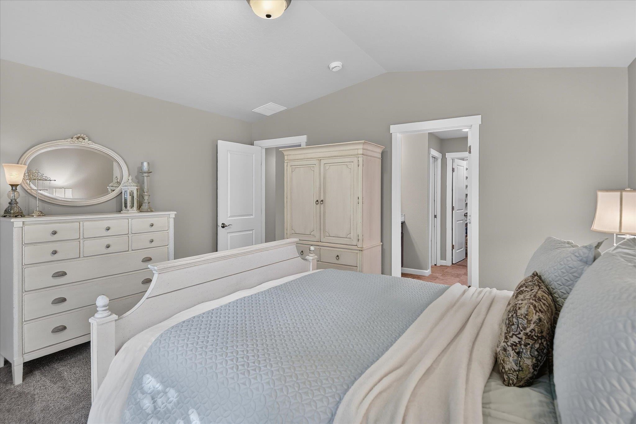 Staged bedroom with a white bed, pale blue bedding, and matching white dresser and wardrobe.