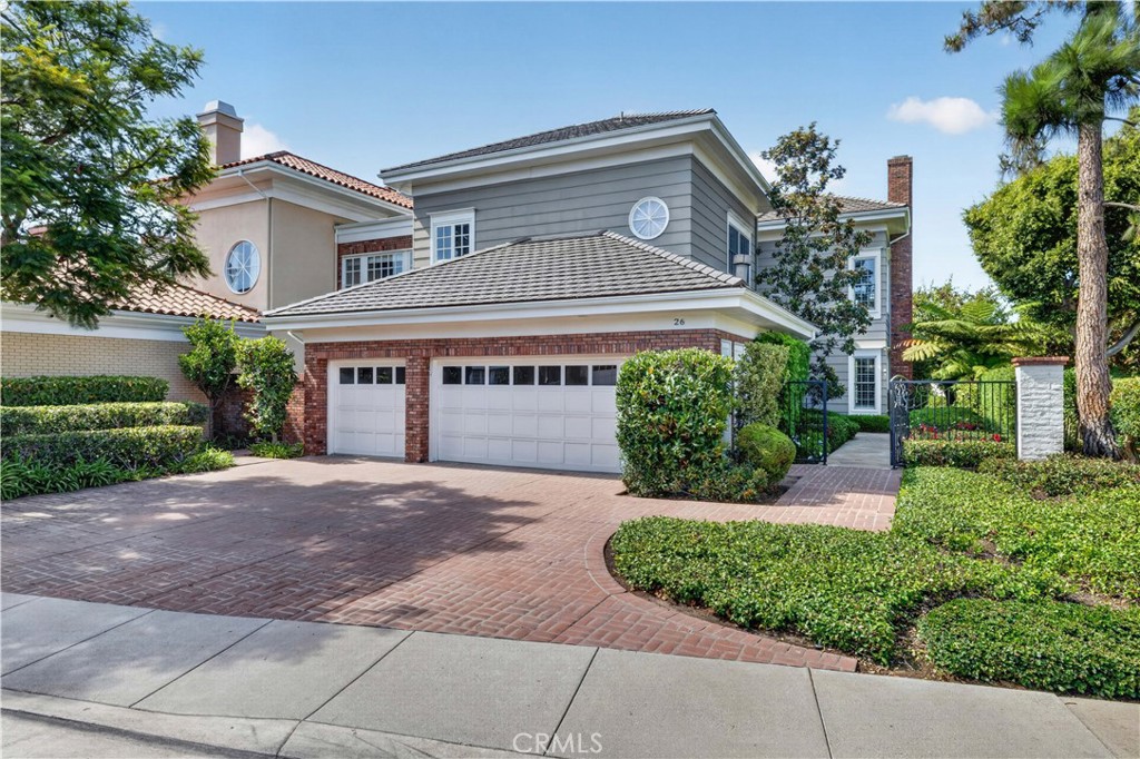 Two-story gray and brick home with a broad driveway, double garage, and landscaped front yard.