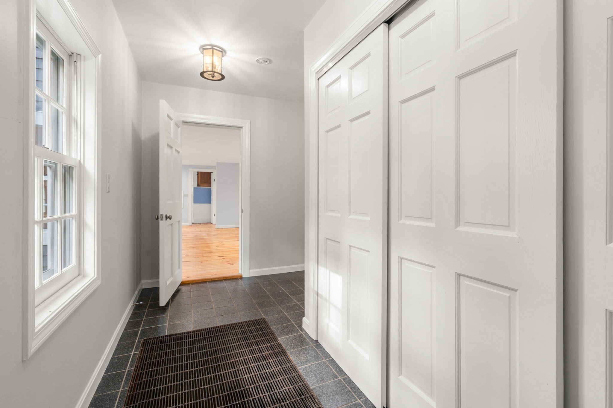 Entry hall with dark tile floors, a large window, and white paneled closet doors.
