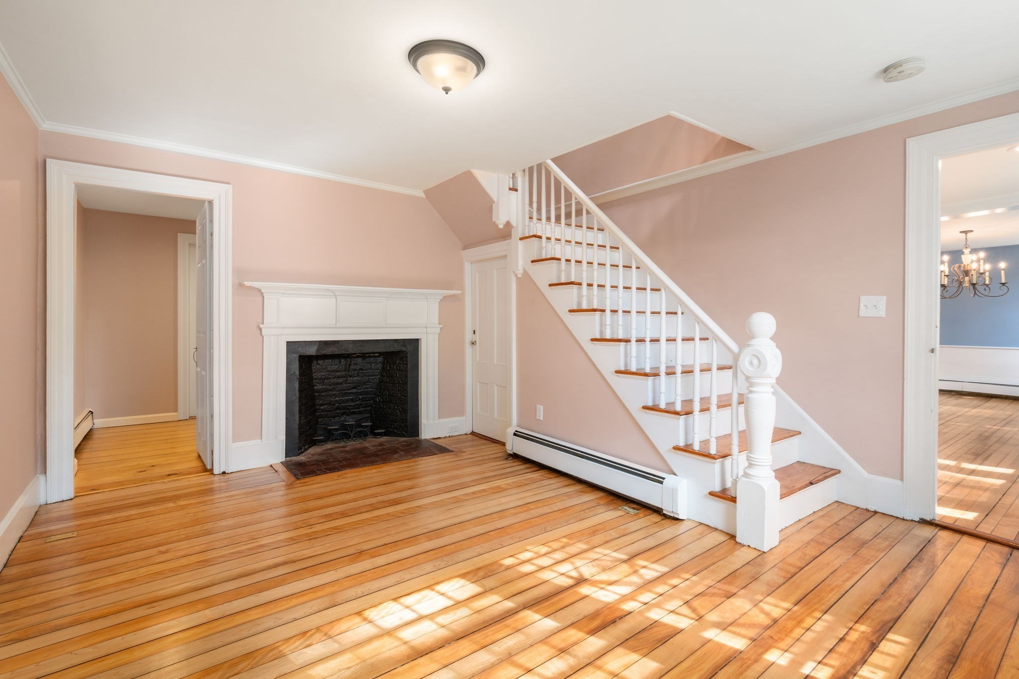 Entry hall with hardwood floors, a white staircase, and a fireplace.