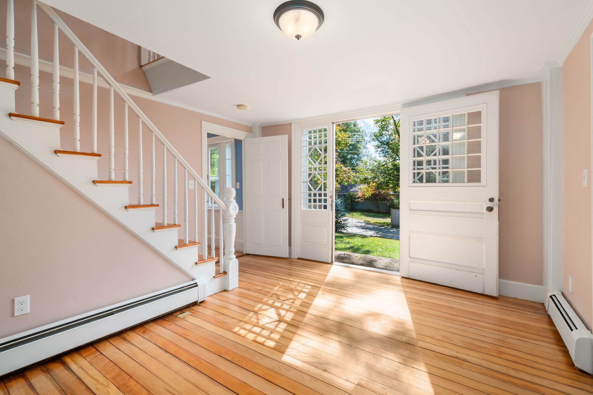 Entryway with a white staircase, hardwood floors, and an open door to the yard.
