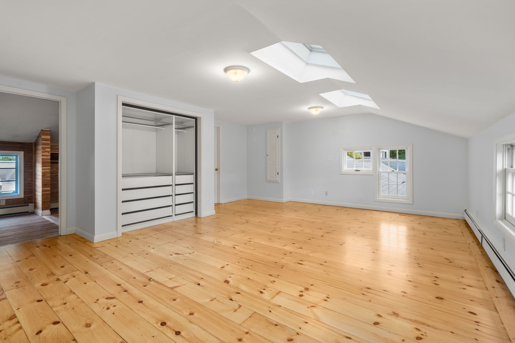 Attic bedroom with pine floors, a built-in closet, and two skylights.