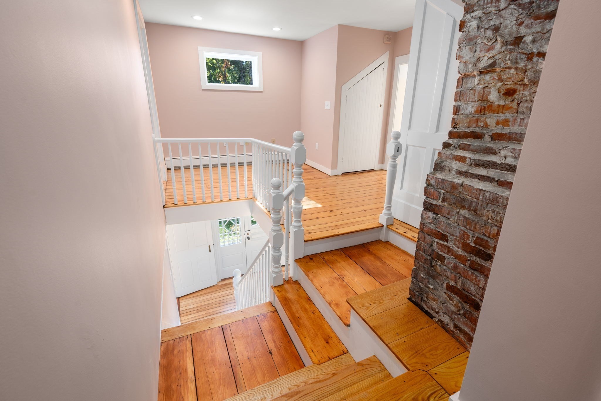 Wooden stairway with white railings and an exposed brick chimney.