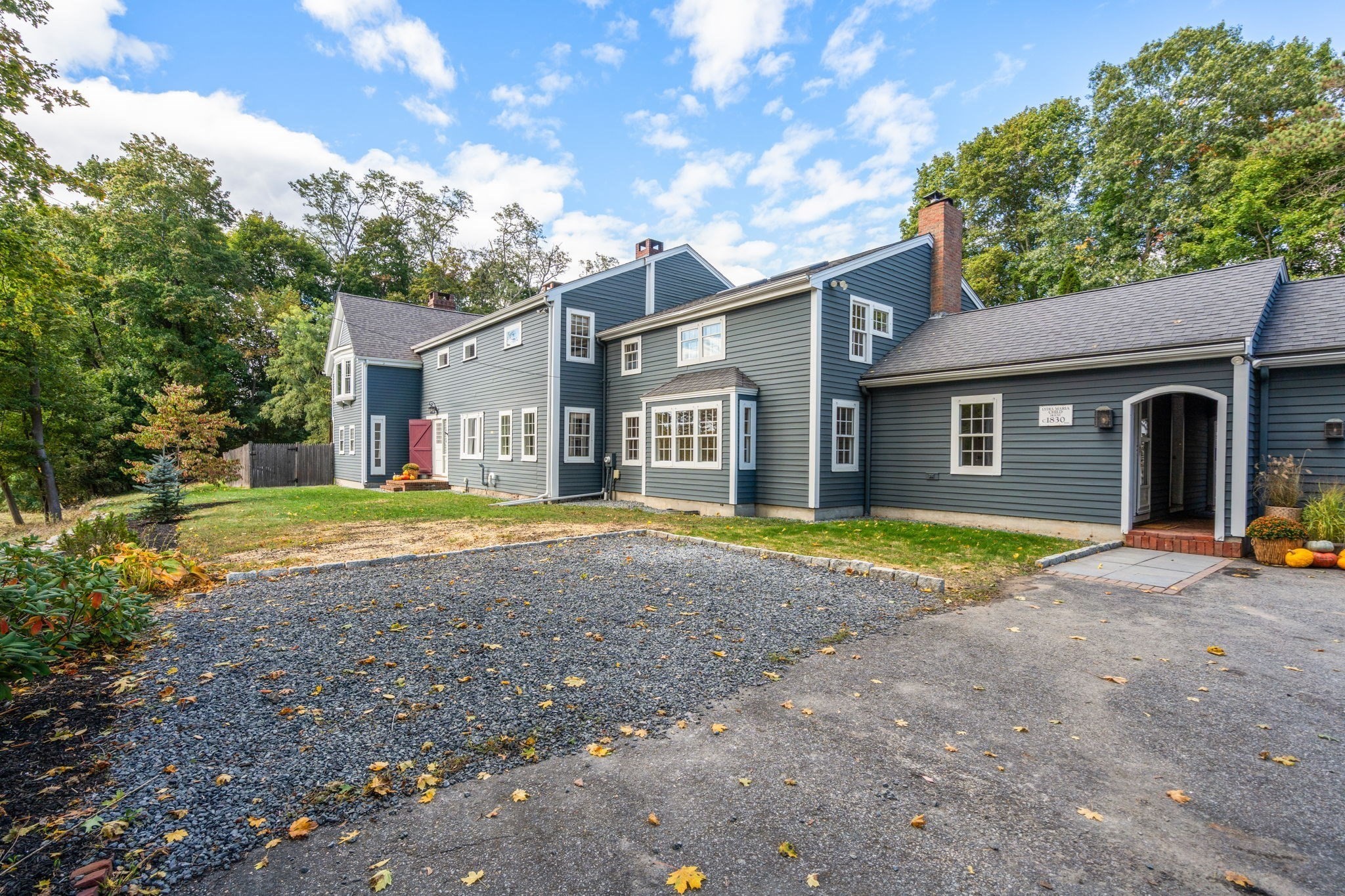 Blue-gray clapboard house with white trim, a gravel driveway, and a covered entrance.
