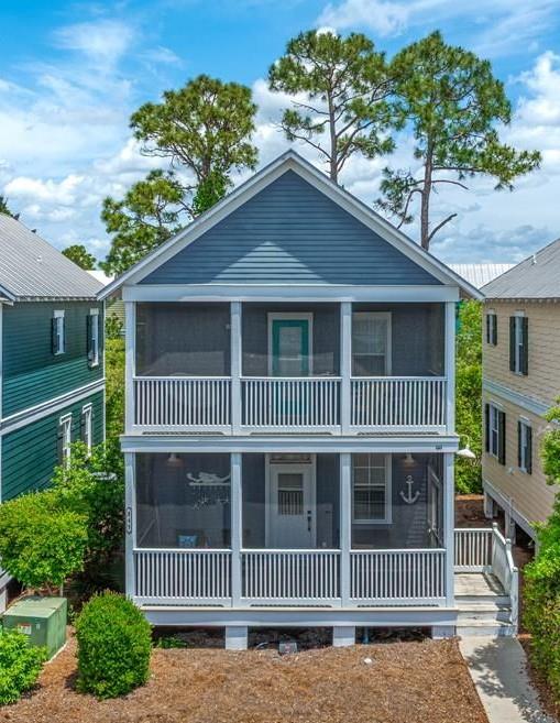 Blue two-story coastal house with white-trimmed screened porches and anchor decorations on the lower porch.