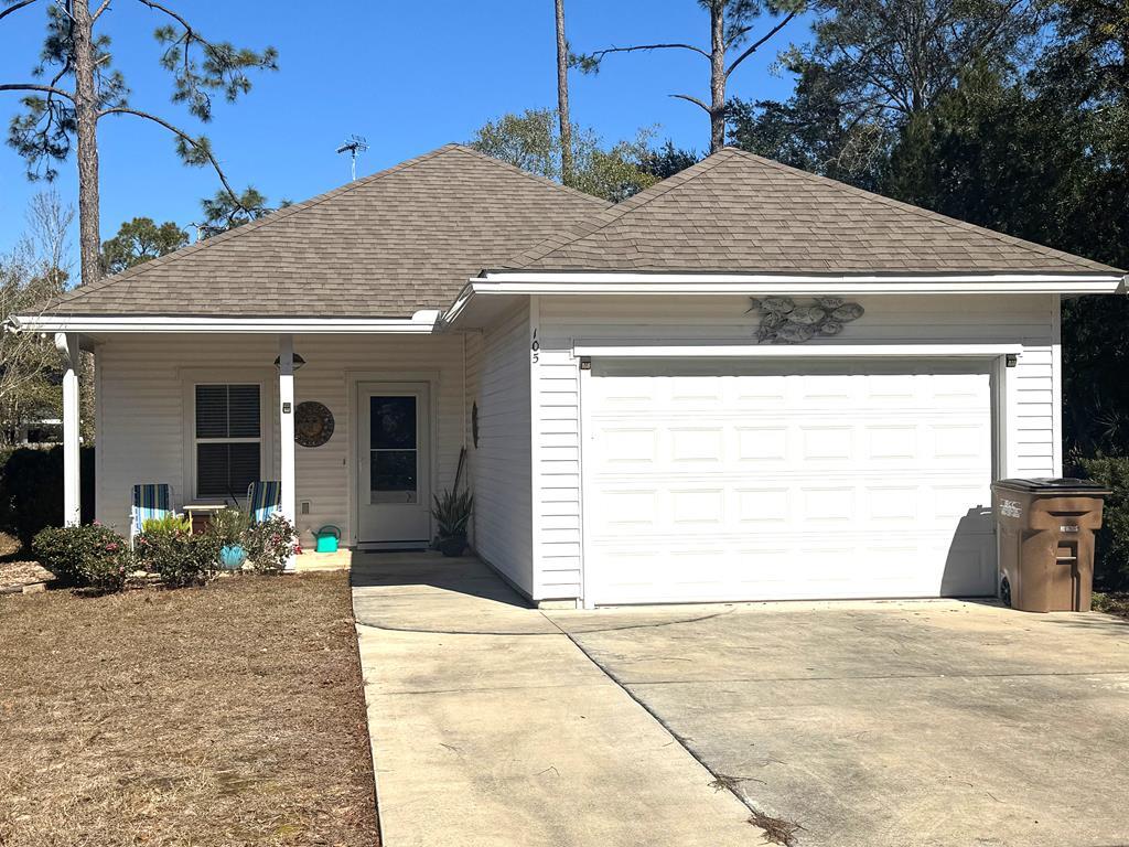 Single-story home with a white double garage, wide concrete driveway, and small front porch.
