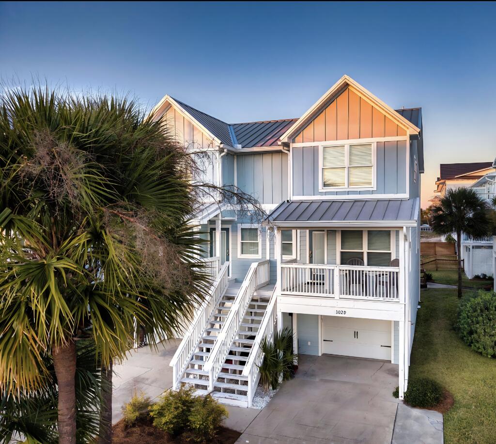 Two-story coastal home with peach gables, blue siding, exterior stairs, and a covered porch.