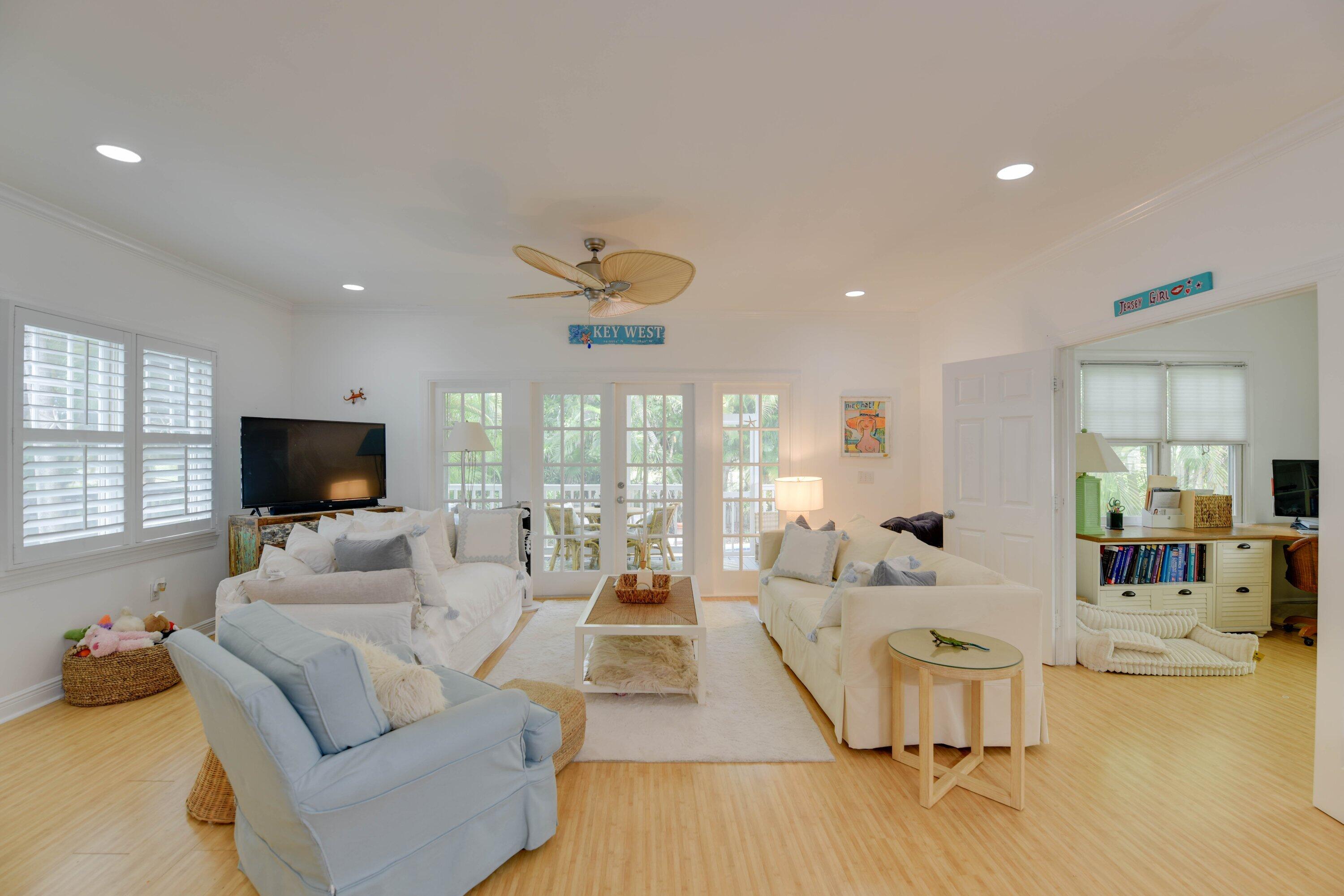 Living room with white sofas, a pale blue armchair, and French doors opening to a patio.