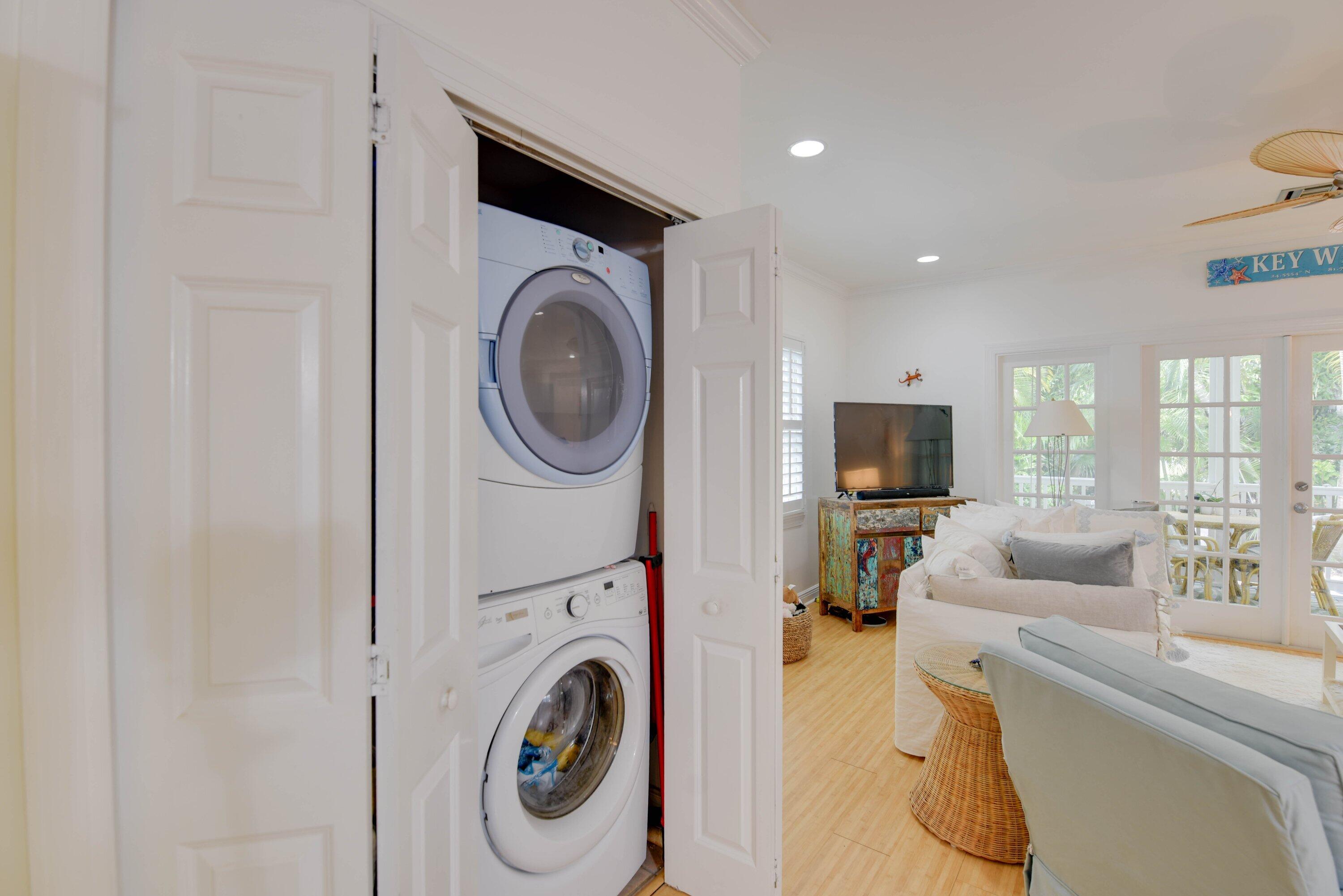 Living room with a stacked washer and dryer in an open closet and glass doors to a patio.