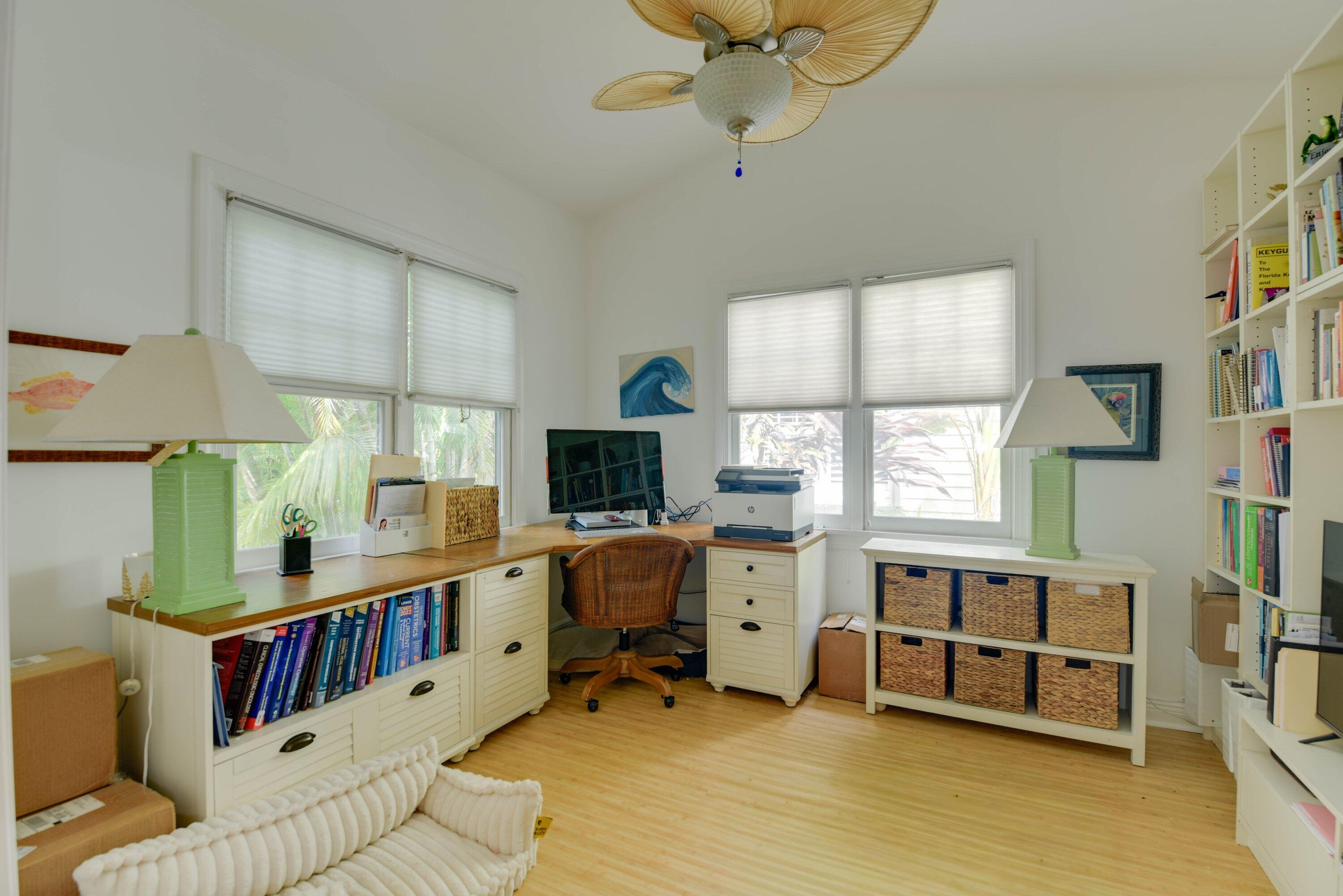 Bright home office with built-in bookshelves, a wood counter, and a wicker desk chair.