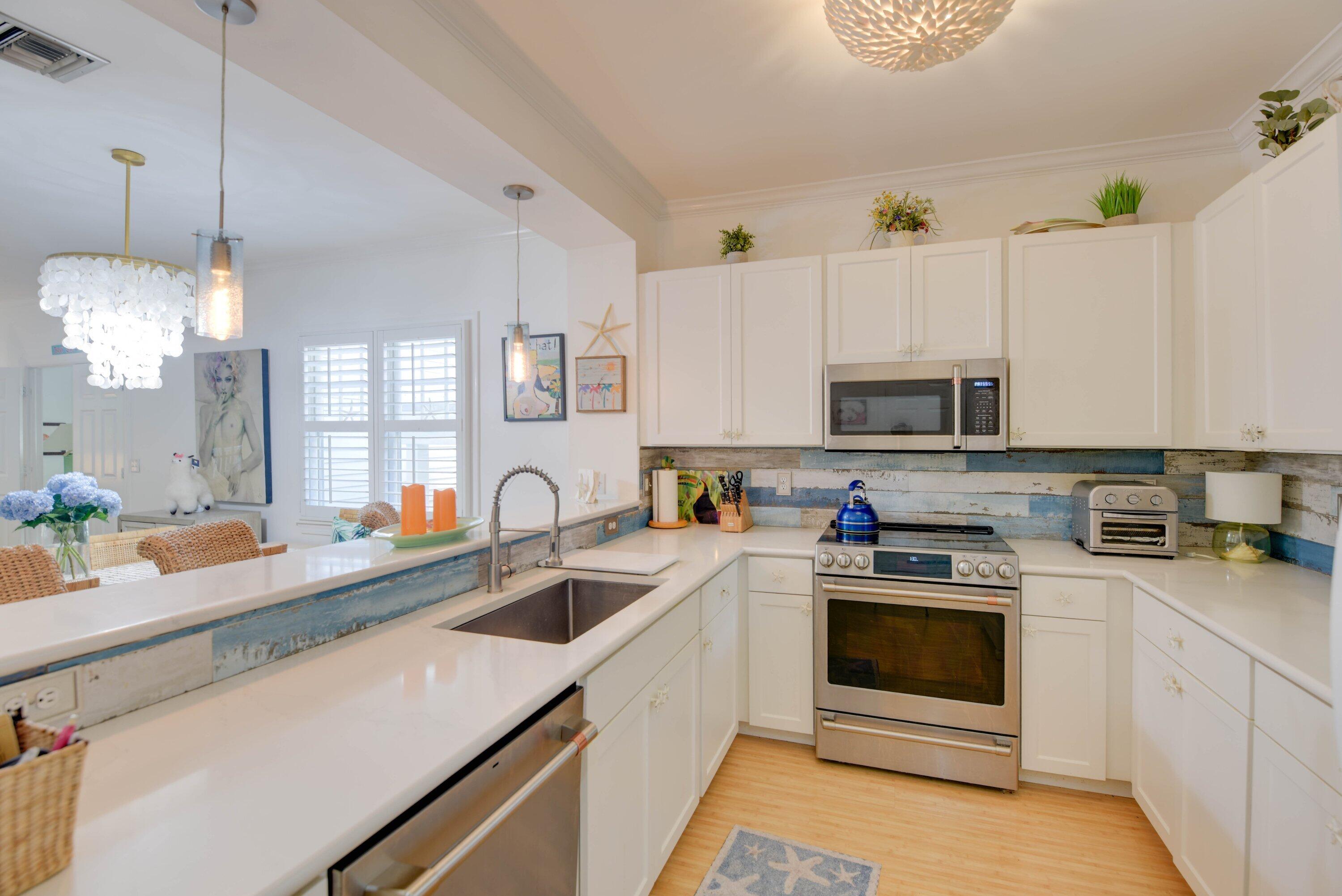 Bright white kitchen with blue wood backsplash, stainless appliances, and an adjoining dining area.