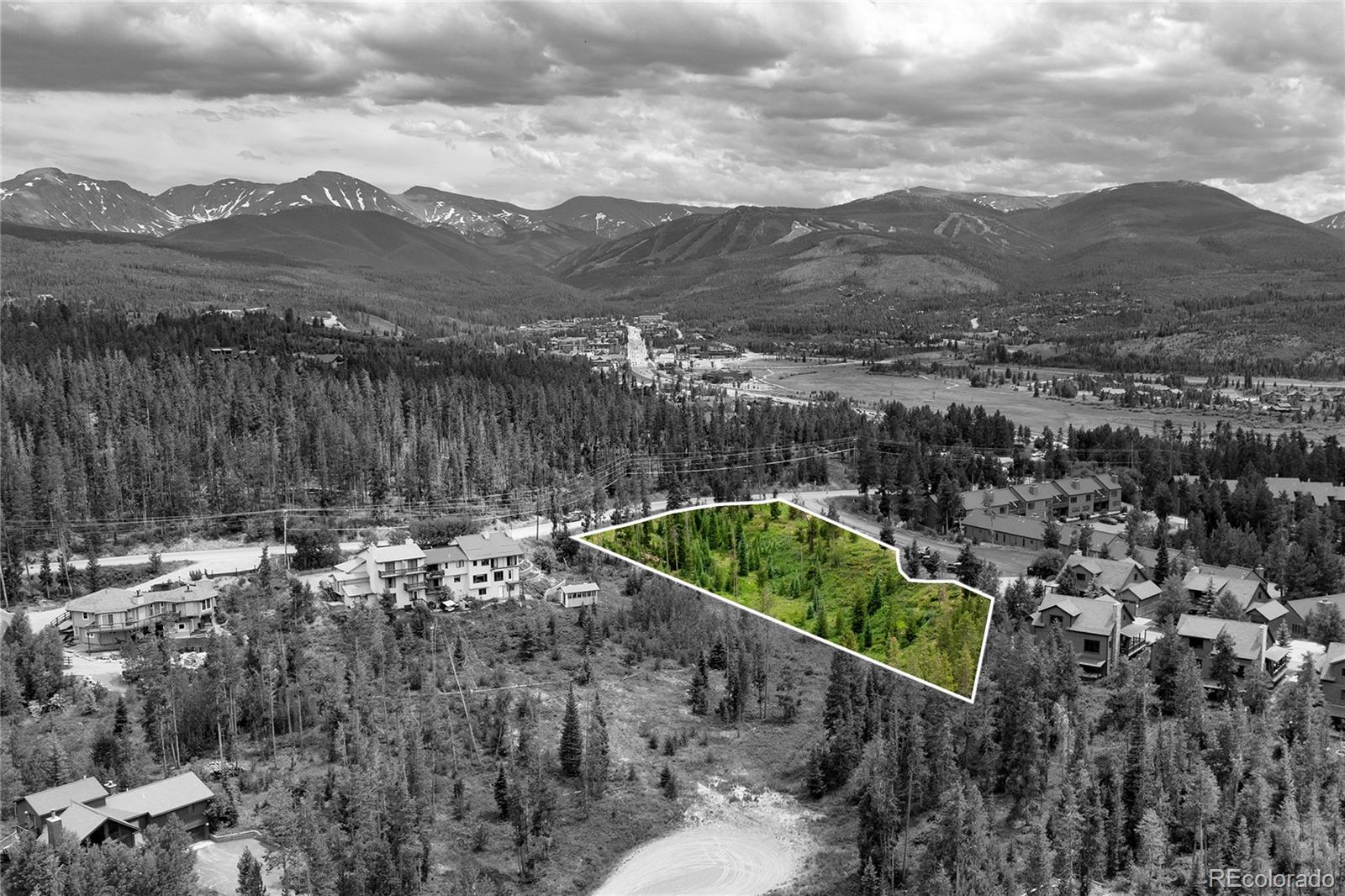 Wooded vacant parcel outlined in white, with mountain valley views and neighboring homes.