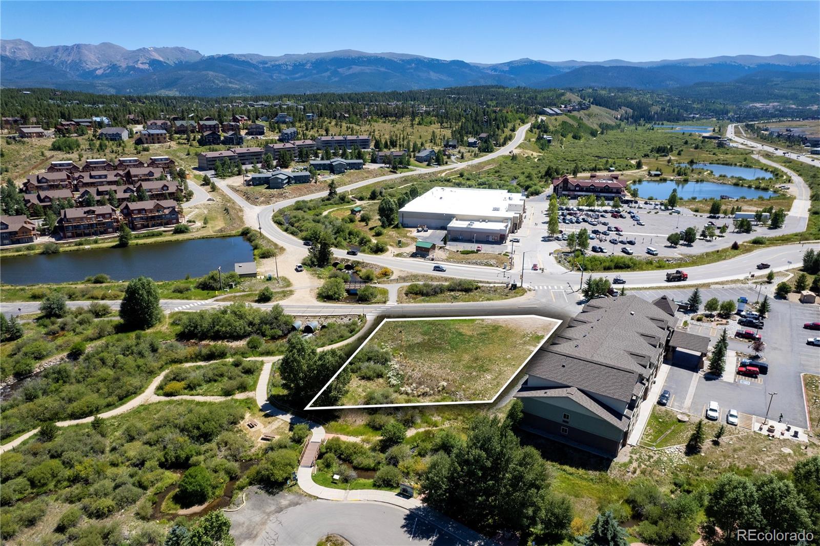Vacant land parcel outlined in white, with ponds and mountain ranges in the distance.
