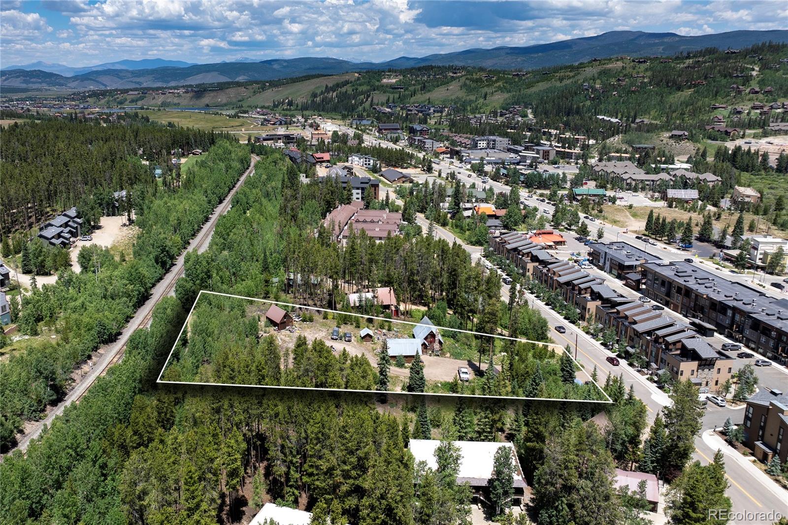 Aerial view of the outlined wooded property beside Winter Park’s town center, with mountains beyond.