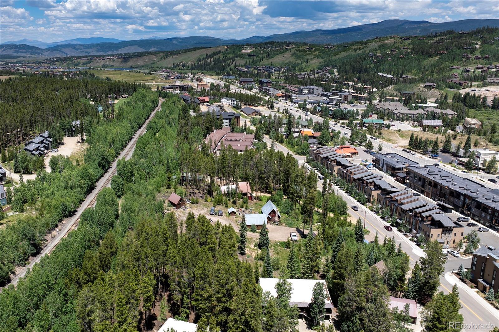 Aerial view of Winter Park neighborhoods, dense pine forest, railway, and surrounding mountain ridges.