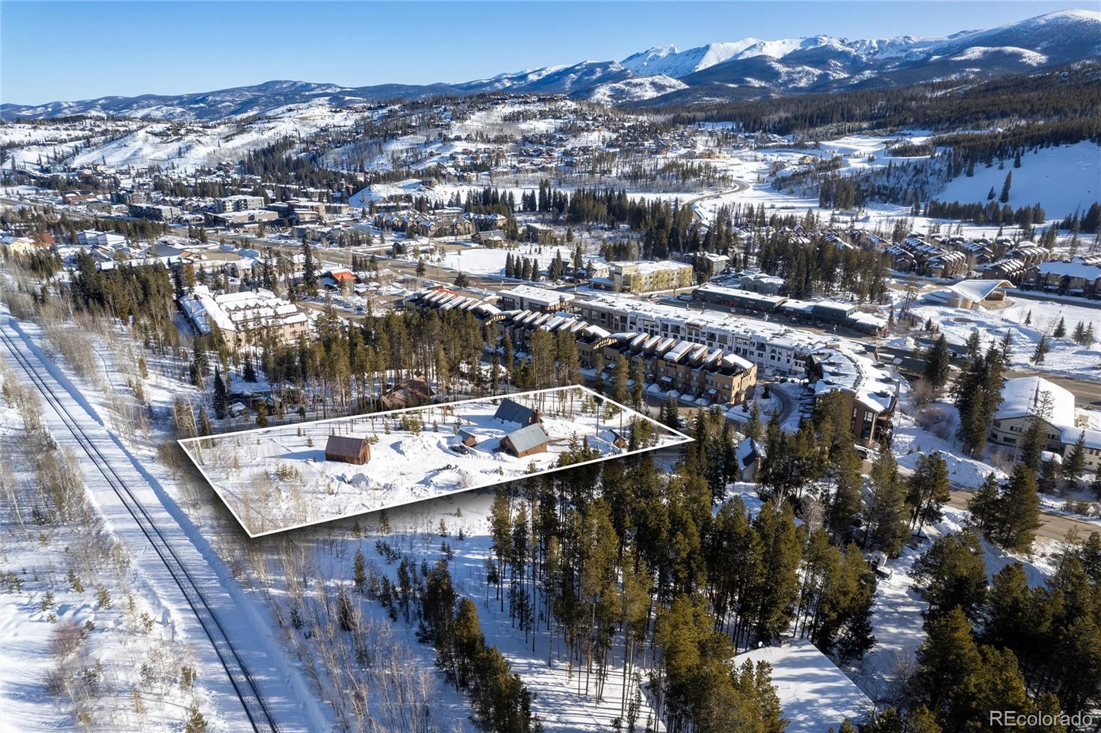 Snow-covered property outlined in white, with two small buildings and mountain views.