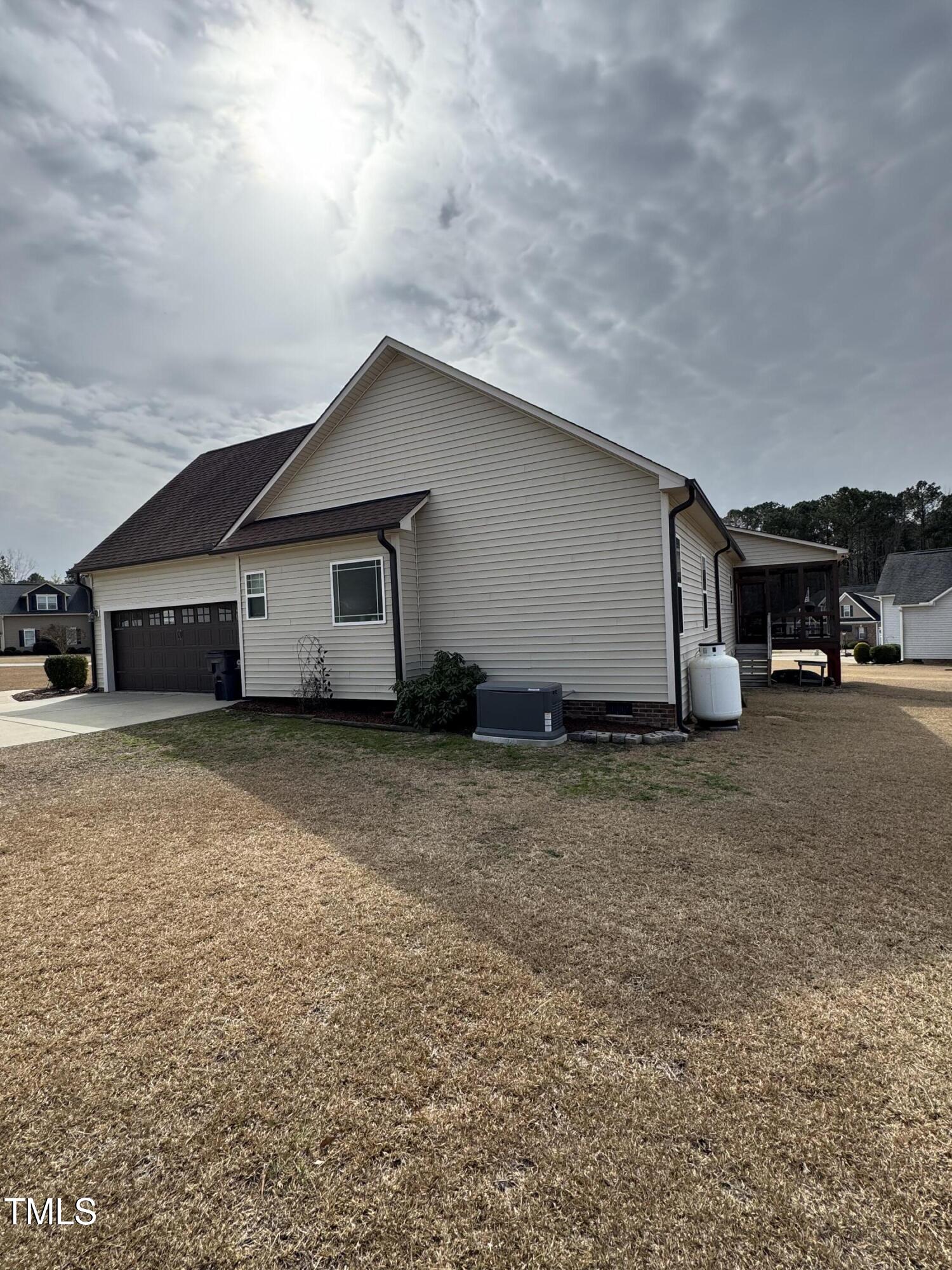 House side and rear with dark garage door, screened porch, and broad lawn.