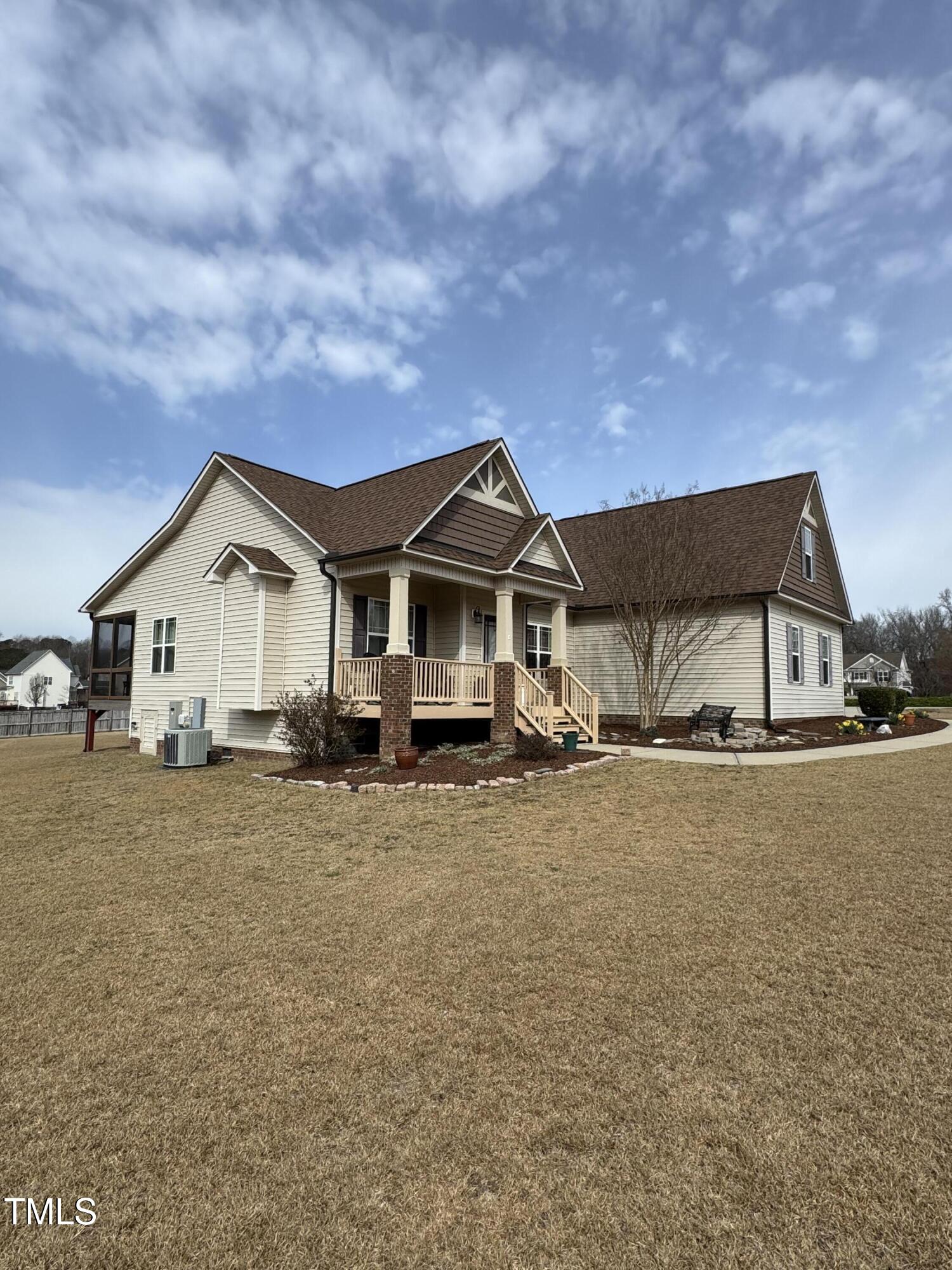 House exterior with a raised covered porch, brick supports, and a broad dormant lawn.