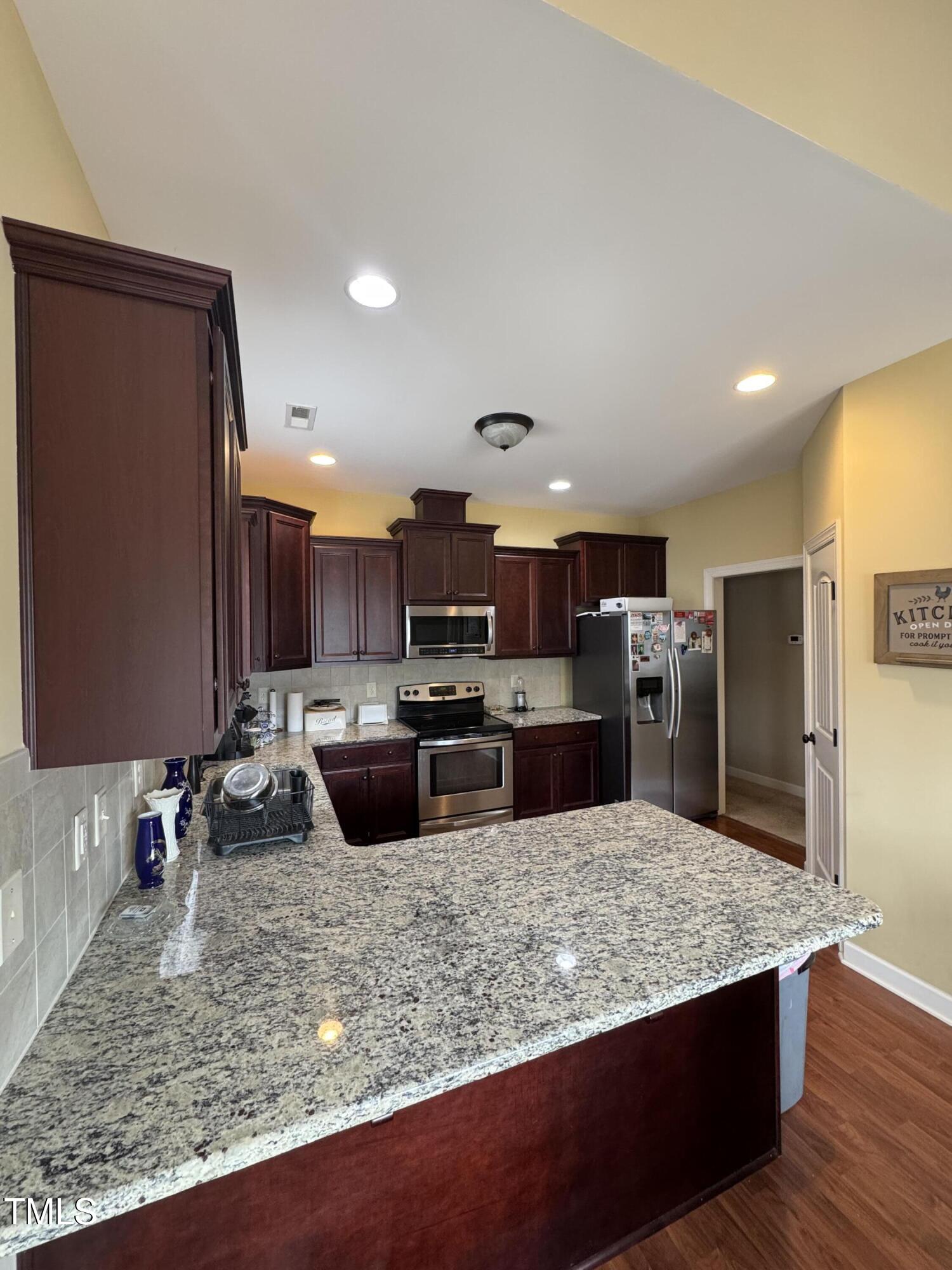 Kitchen with dark wood cabinets, stainless steel appliances, and a large granite island.