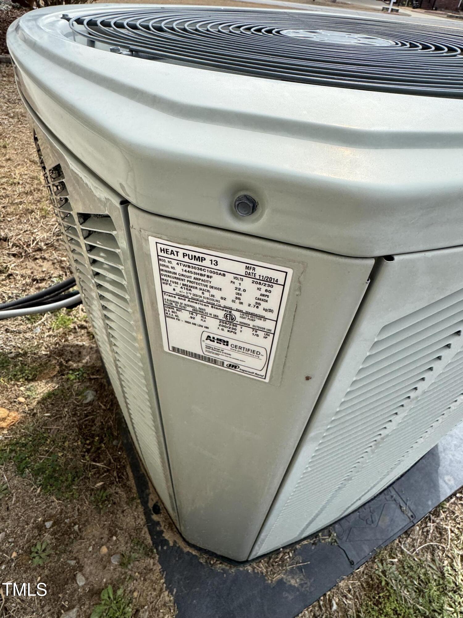 Outdoor heat pump condenser with its equipment label visible.