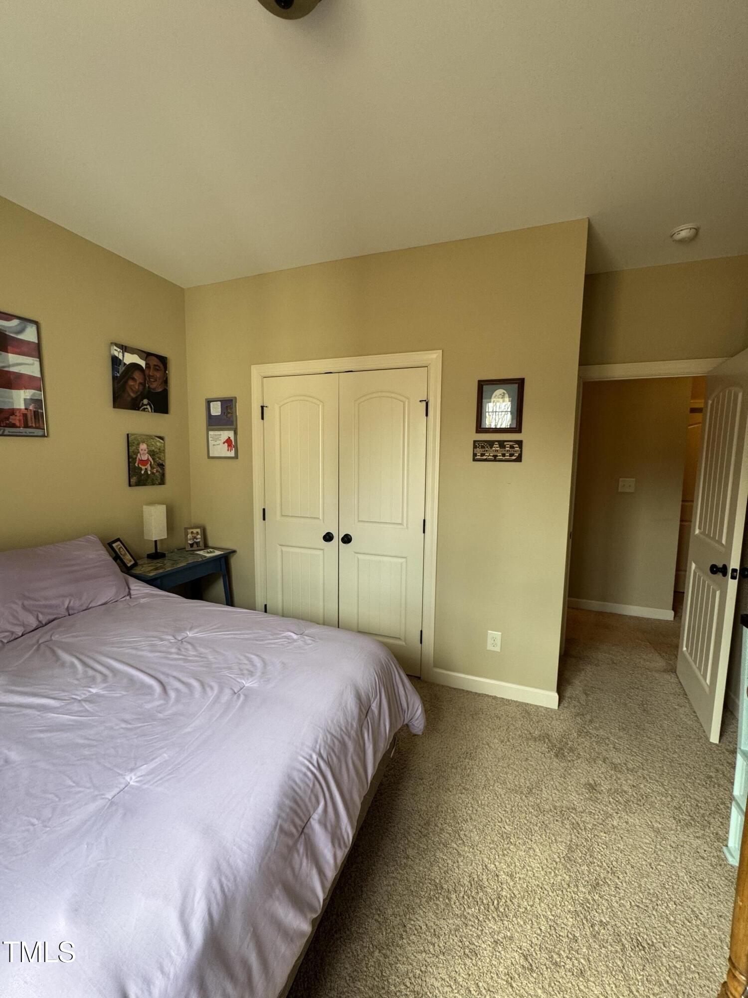 Bedroom with a lavender bedspread, white double closet doors, and an open doorway to the hall.