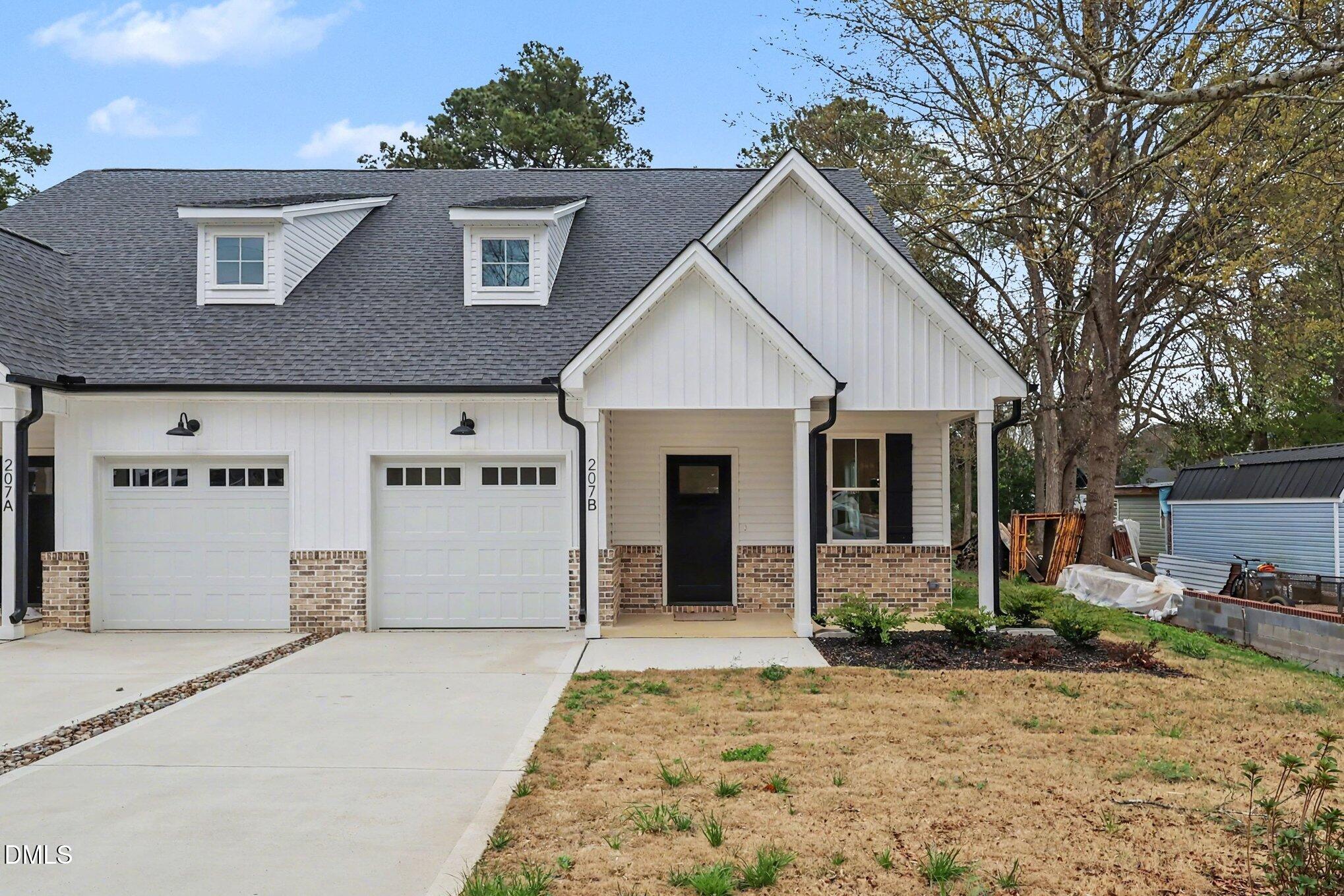 White attached homes with brick accents, two garage doors, and a shared driveway.