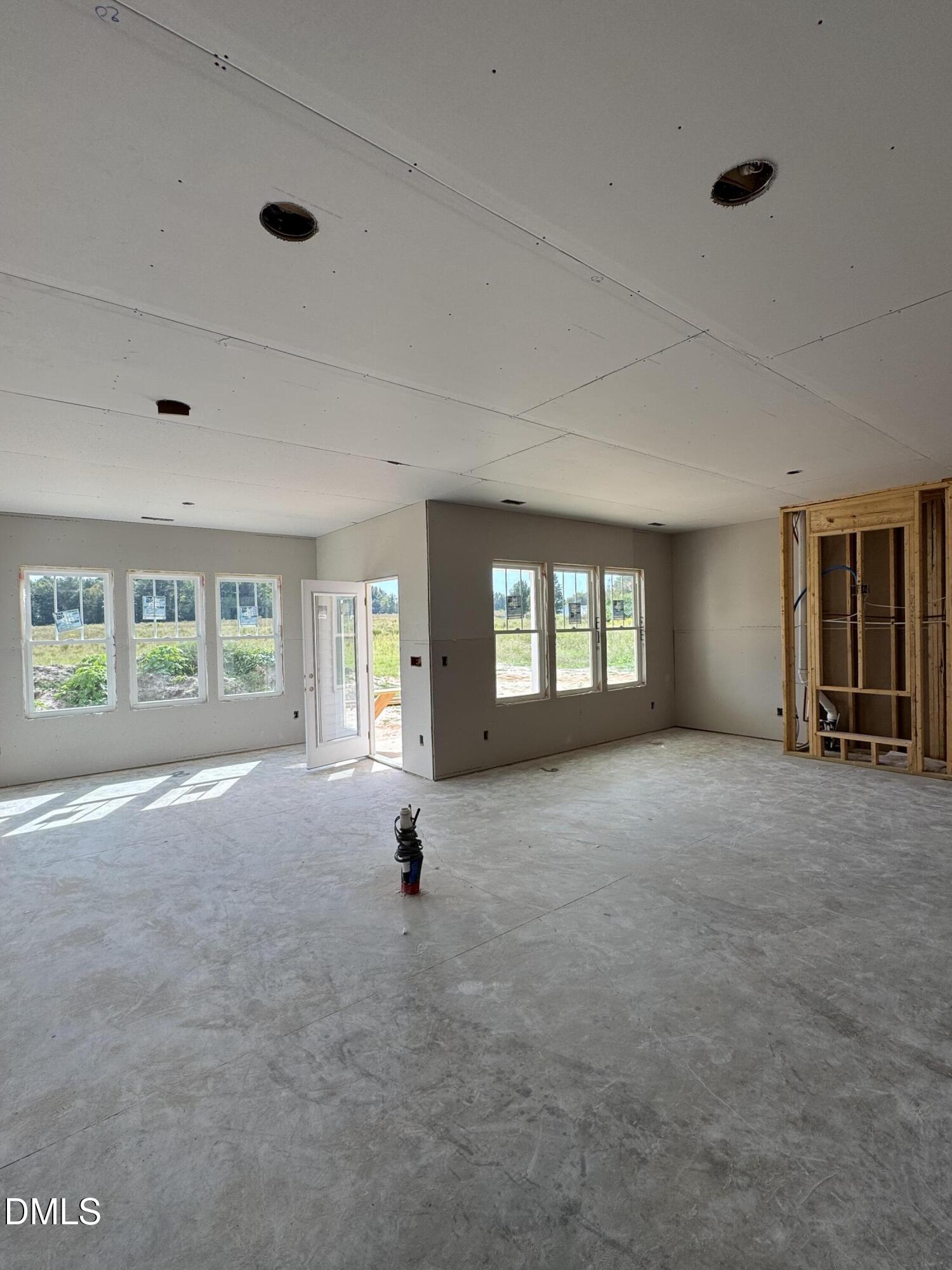 Unfinished interior with concrete floor, multiple windows, and exposed framing.